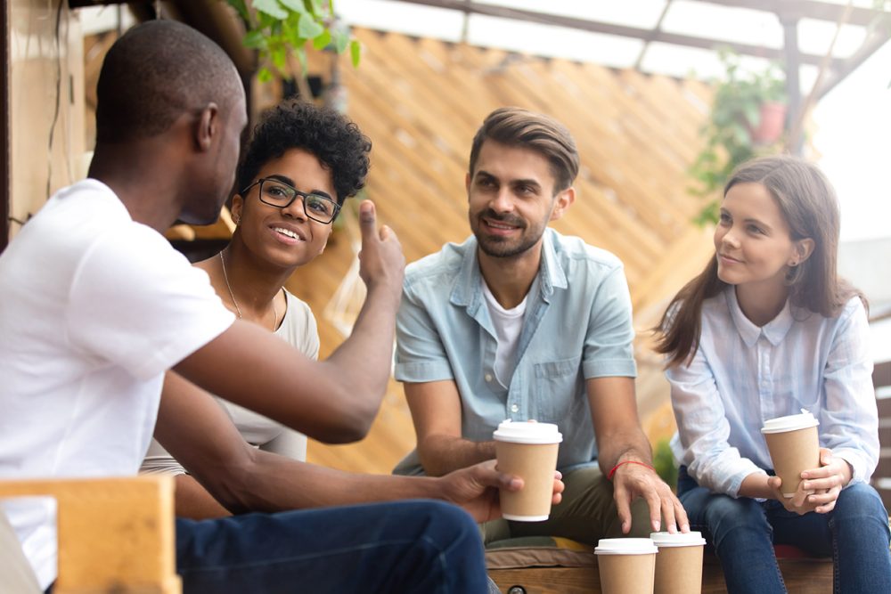 African American man showing thumb up to friends in cafe